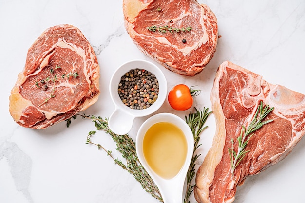 Three delicious steaks ready to grill on a white marble surface