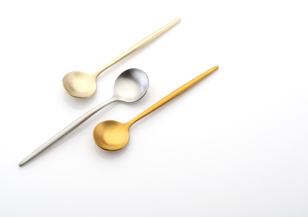 Three dessert spoons of different colors on a white background, copy space