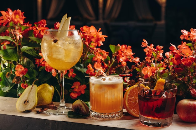 Tre diversi bellissimi cocktail in colori caldi su uno sfondo di fiori