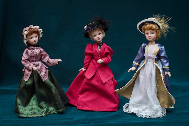 Three dolls in classic vintage dresses and hats on dark