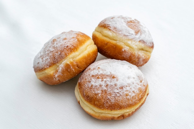 Three donuts sprinkled with icing sugar on a light surface
