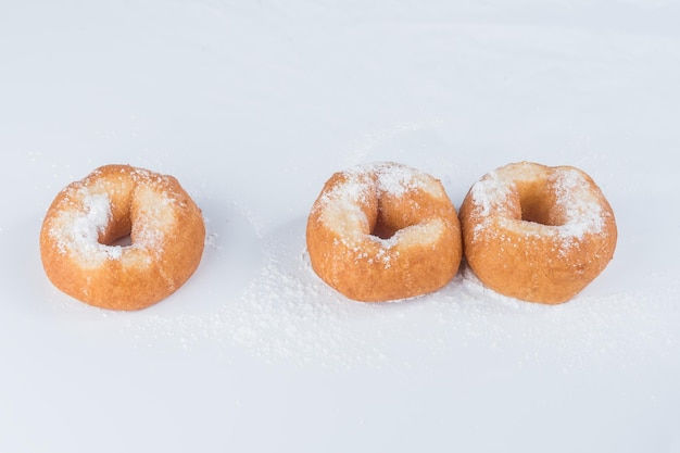 Three donuts with powdered sugar on a light background