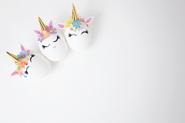 Three Easter eggs decorated with unicorn stickers on a white background Copy space Top view