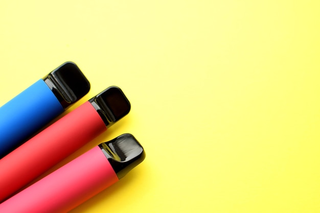 Three electronic cigarettes on a yellow background. Place for your text.