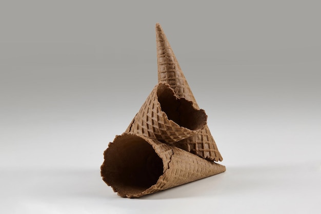 Три пустых вкусных коричневых вафельных рожка для мороженого, изолированные на белой концепции макета угощений