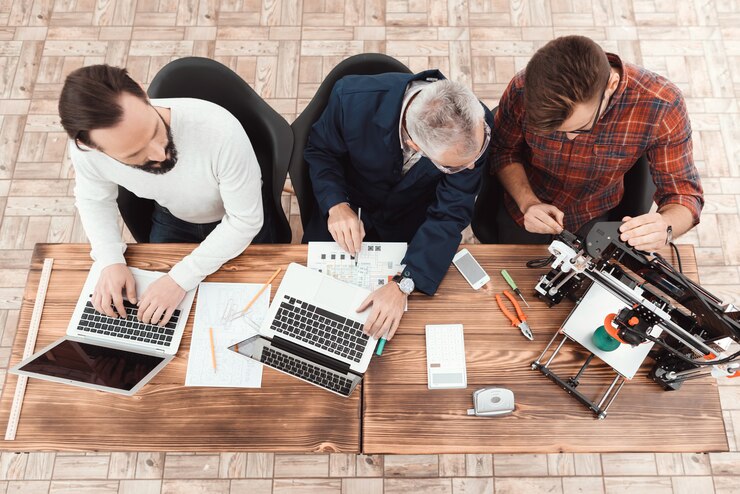 Photo three engineers sit at the table with laptop 