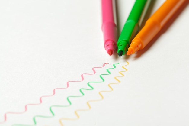 흰색에 그려진 색 표시가있는 분홍색, 주황색 및 녹색의 펠트 펜 3 개