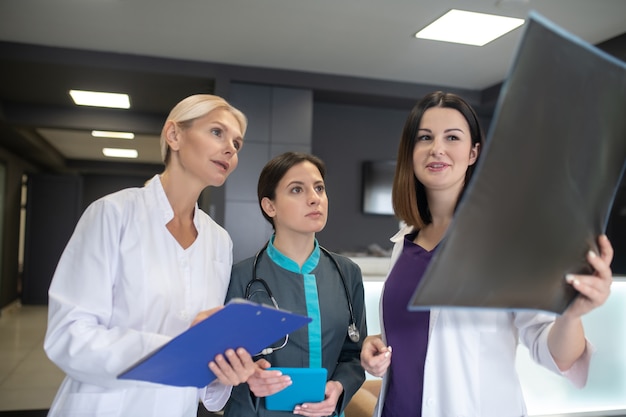 Three female doctors looking involved while discussing xray results