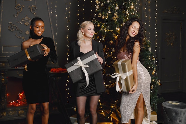 Three female friends in elegant dresses celebrating New Year