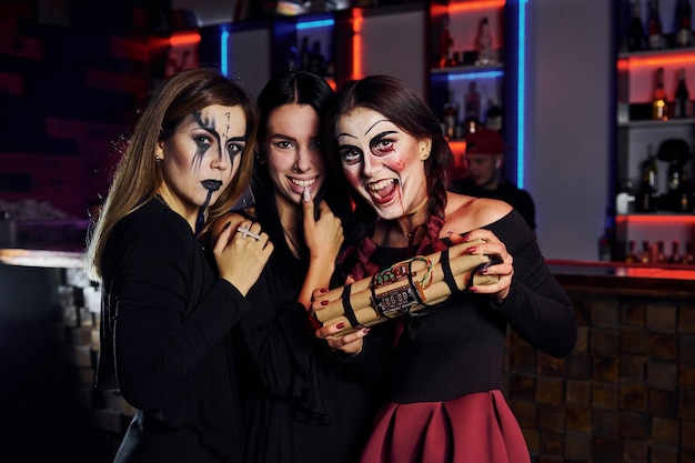 3人の女性の友人が怖い化粧と衣装でテーマ別のハロウィーンパーティーに参加しています。