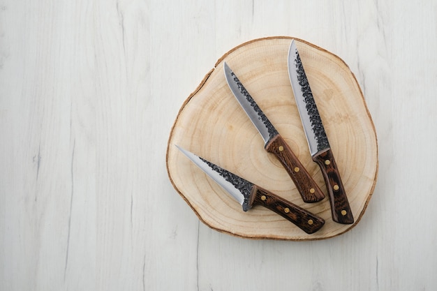 Три кованые ножи мясника на деревянном пне