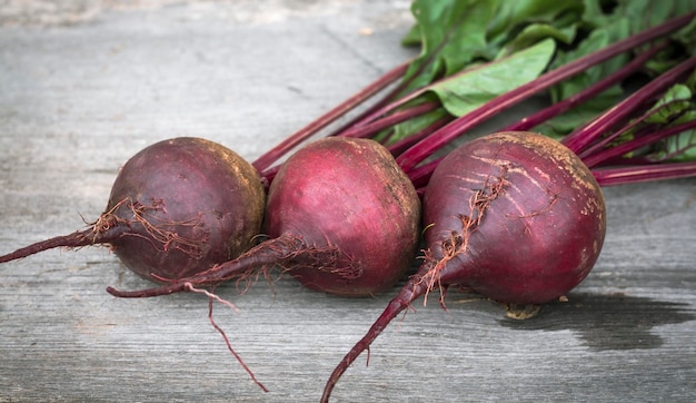 Three fresh beets with tops on a wooden background