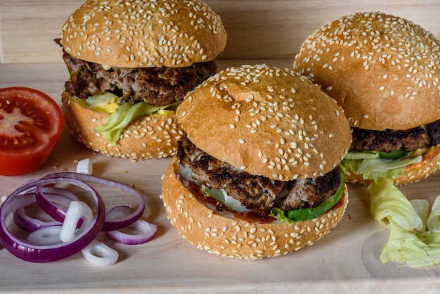 Three fresh burger lay on the board.