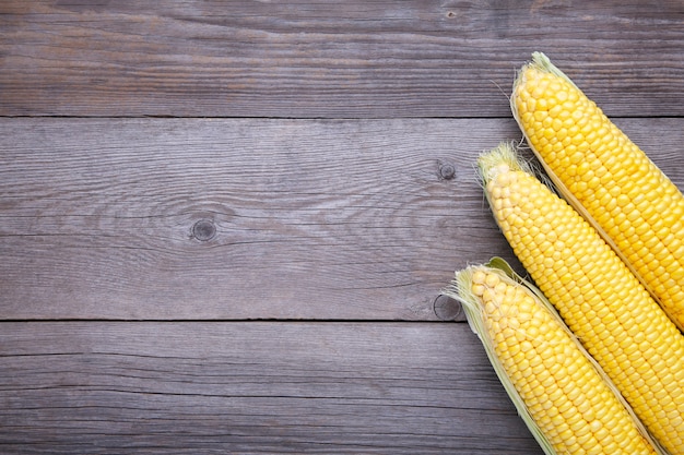 Photo three fresh corn on grey wood