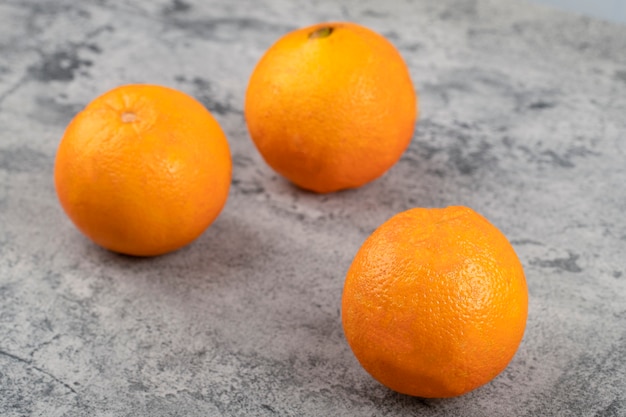 石のテーブルに分離された3つの新鮮な健康的なオレンジ。