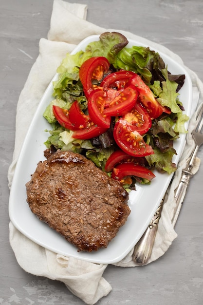 Three fried ground meat with fresh salad on white plate