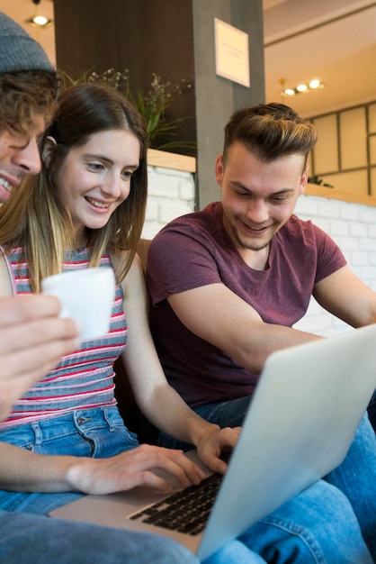 Three friends sharing laptop in a cafe