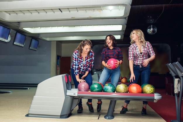 Foto tre amiche attraenti divertenti prendono le palle da bowling