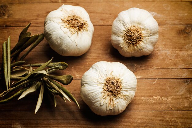 Three garlic bulbs on a wooden table in a top view