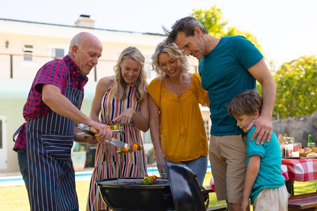 Photo three generational caucasian family barbecuing together in the garden