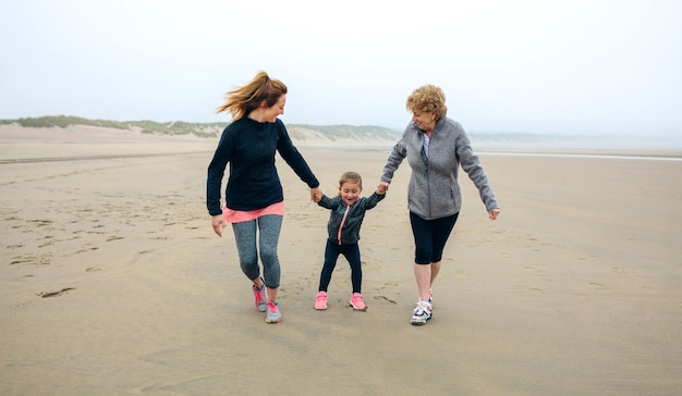 Three generations female running on the beach in autumn