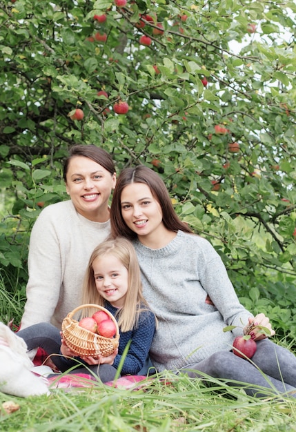 Three generations of women of same family in apple orchard at picnic