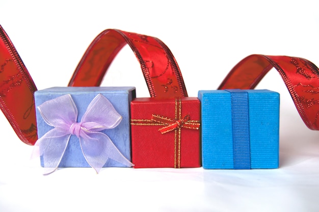 Three gift boxes, red, blue and violet, with decorative tape behind