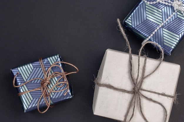 Three gift boxes with copy space in the upper left One of kraft gray paper tied with hemp and two of blue gift paper