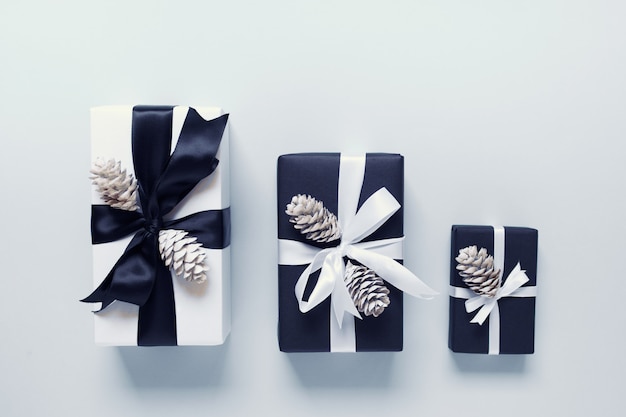 Three gift boxes with pine cones on white