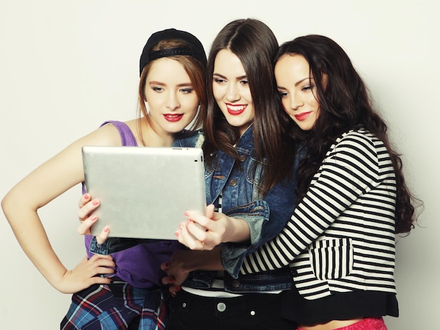 Three girls friends taking selfie with digital tablet studio shot over gray vackground