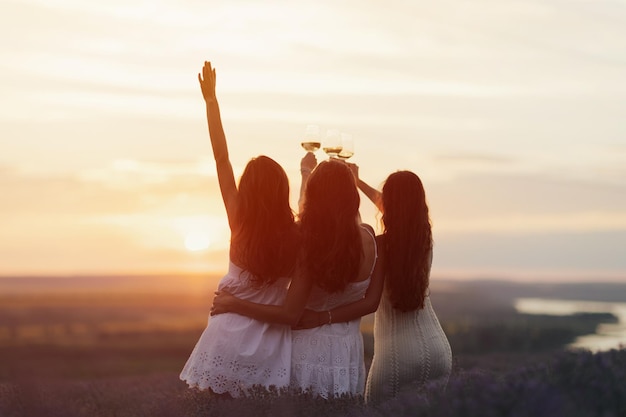 Three girls in a lavender field holding a glasses of wine