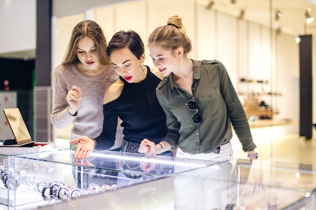 Photo three girls looking at showcase at shopping in the mall