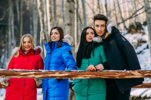 Four friends, one boy and three girls rolling big snowball against beautiful mountains landscape Four friends, one boy and three girls rolling big snowball against beautiful mountains landscape