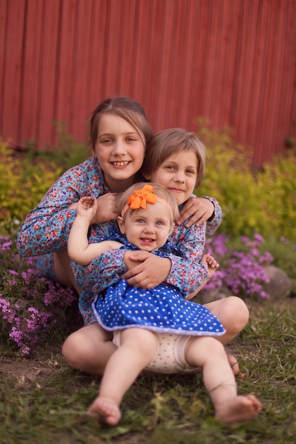 Three girls   sitting near   wooden wall in  spring.Happy family concept