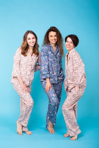 Three  girls wearing colorful pajamas having fun on blue