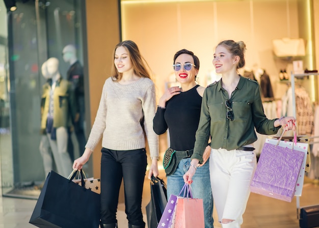 Three glamorous girlfriends with shopping paperbags walking