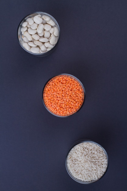 Three glass jars with different groats. Dark blue background.