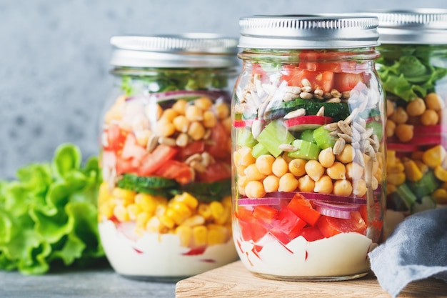 Three glass jars with layering various vegan salads for healthy lunch The concept of fitness and vegetarian food