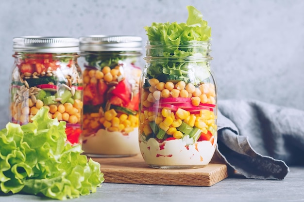 Three glass jars with layering various vegan salads for healthy lunch The concept of fitness and vegetarian food