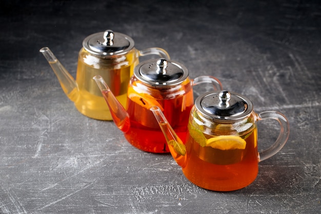 Photo three glass teapots with different tea with lemon