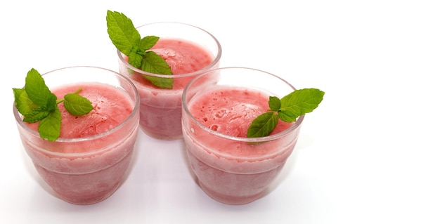 Three glasses of homemade strawberry yogurt ice cream isolated with a mint leaf on white background