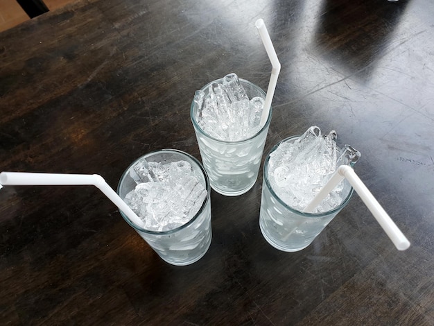 Tre bicchieri di ghiaccio con una cannuccia sul tavolo