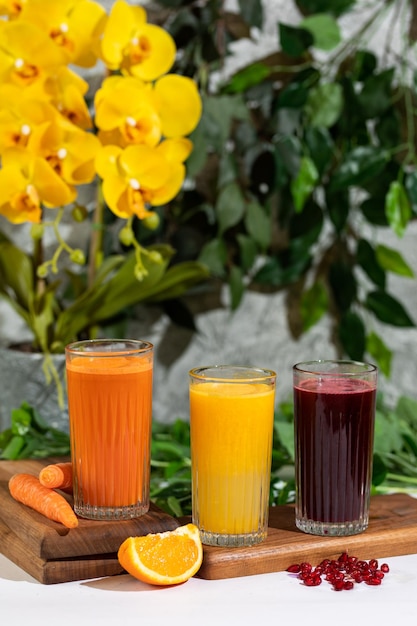 Three glasses of juice with a yellow flower behind them.