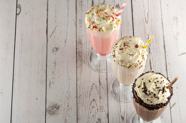Three glasses of milkshake with assorted flavors. Chocolate, vanilla and strawberry milkshake.