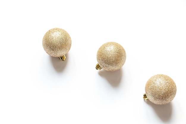 Three golden colored glittering christmas balls on the white background