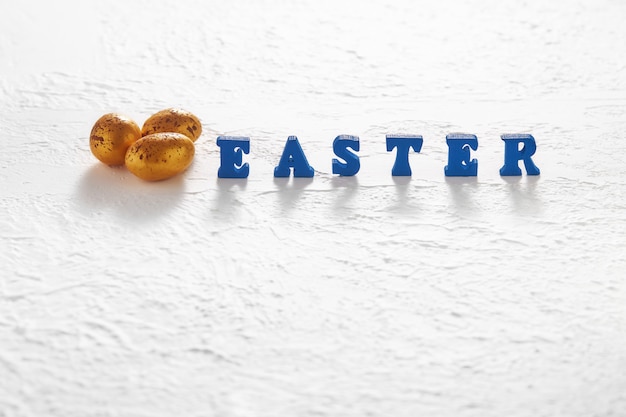 Three golden eggs and a blue easter inscription on a white background as a backdrop