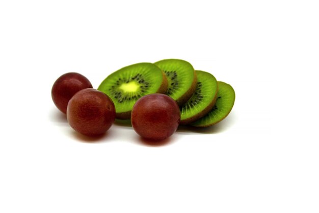 Foto tre uva e fette di kiwi isolate su uno sfondo bianco