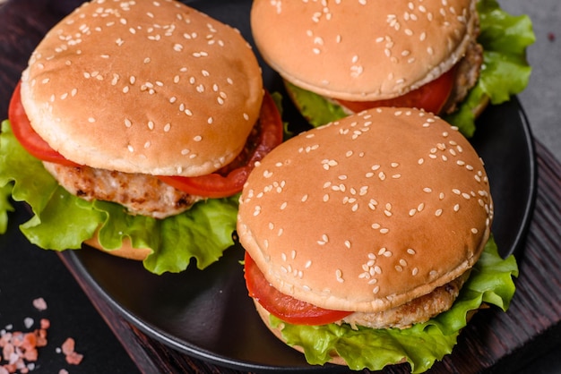 Three hamburger with beef meat burger and fresh vegetables on dark background