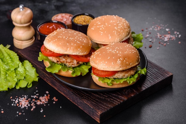 Three hamburger with beef meat burger and fresh vegetables on dark background