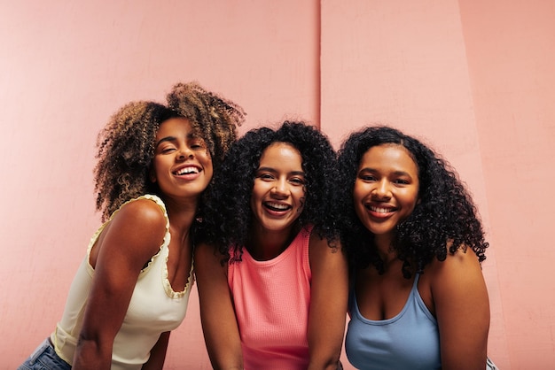 Three happy girls with curly hair Smiling females wearing colorful tshirts looking at the camera